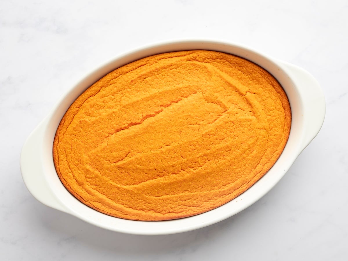 fully baked carrot souffle in white oval baking dish
