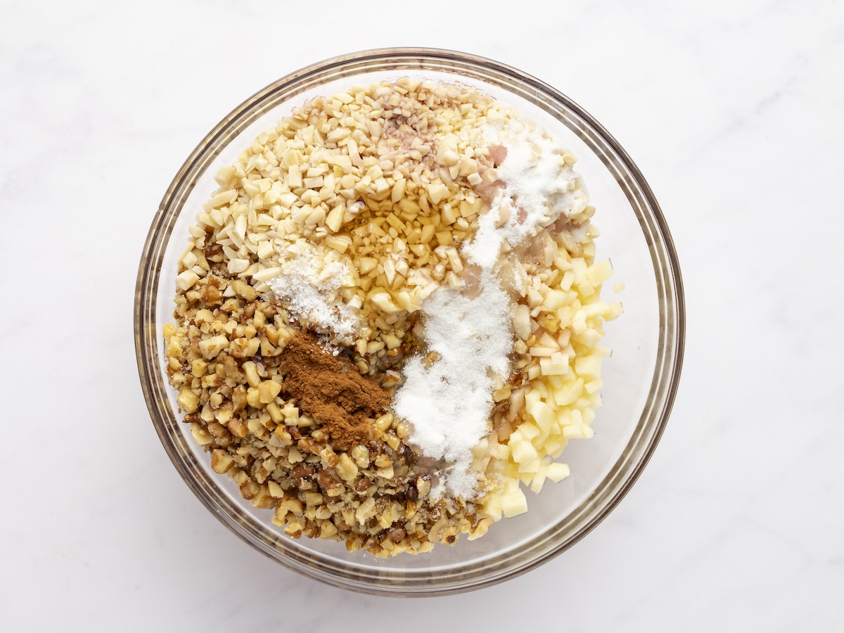 apples, walnuts, almonds, wine, orange juice, honey, sugar, salt, and cinnamon in medium bowl