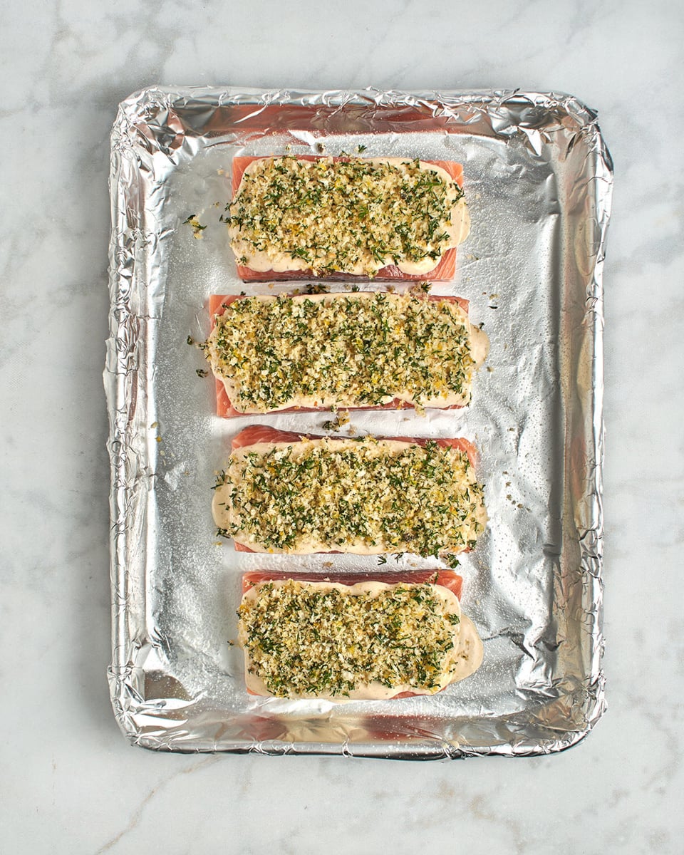 salmon topped with sauce and panko mixture on baking sheet