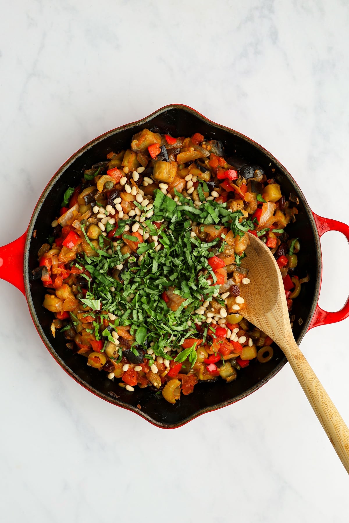 caponata in large skillet with basil and pine nuts on top