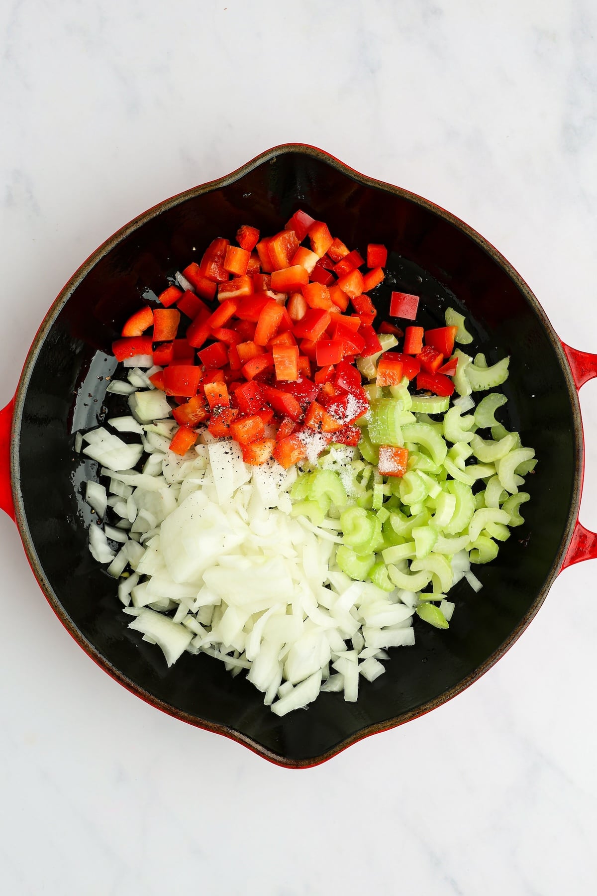 large skillet with uncooked onion, celery, bell pepper, salt, and pepper