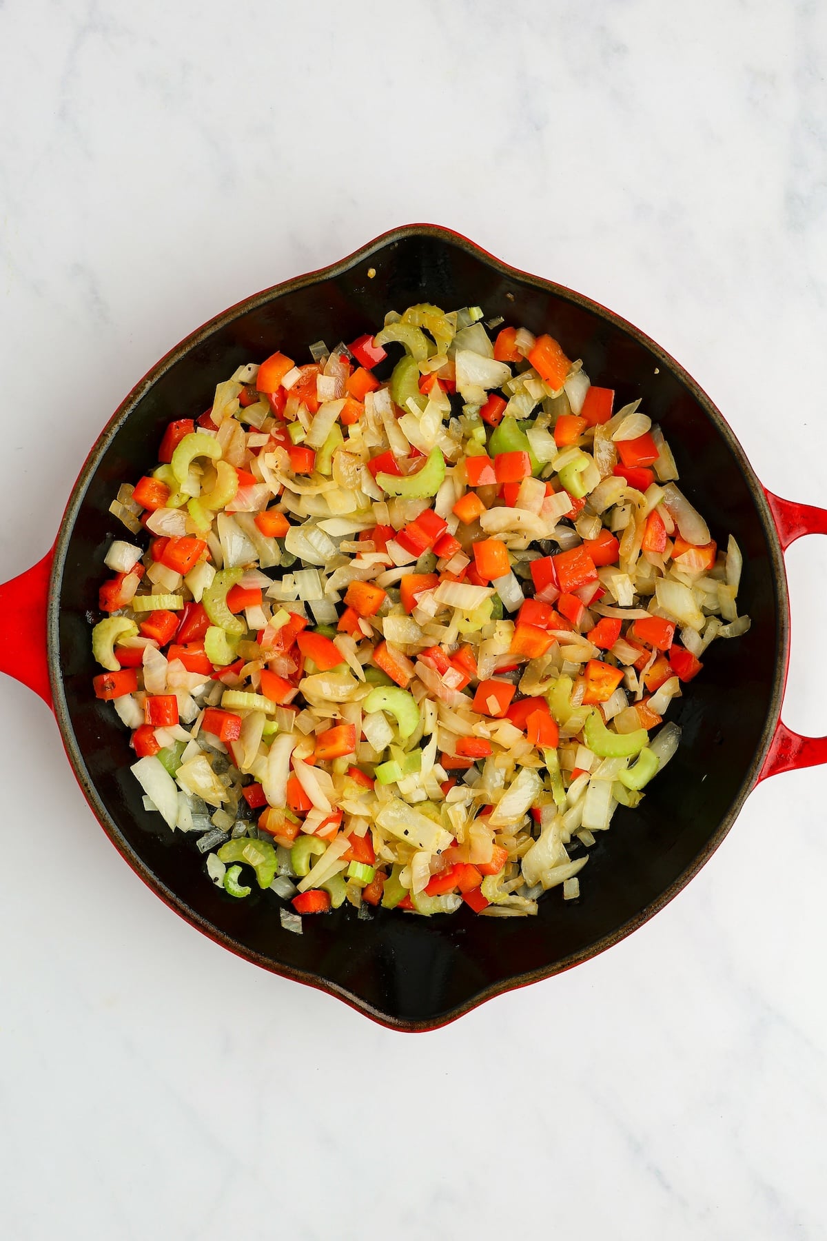 large skillet with softened onion, celery, bell pepper, salt, and pepper