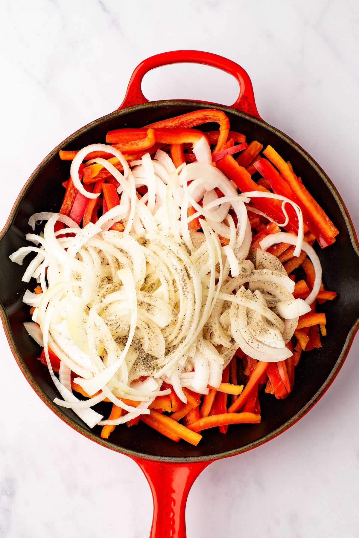 onions and peppers in skillet with salt and pepper