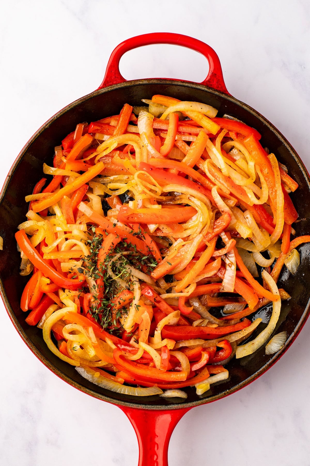 onions and peppers in skillet sprinkled with thyme
