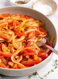 onions and peppers in bowl with salt, pepper, and thyme on side