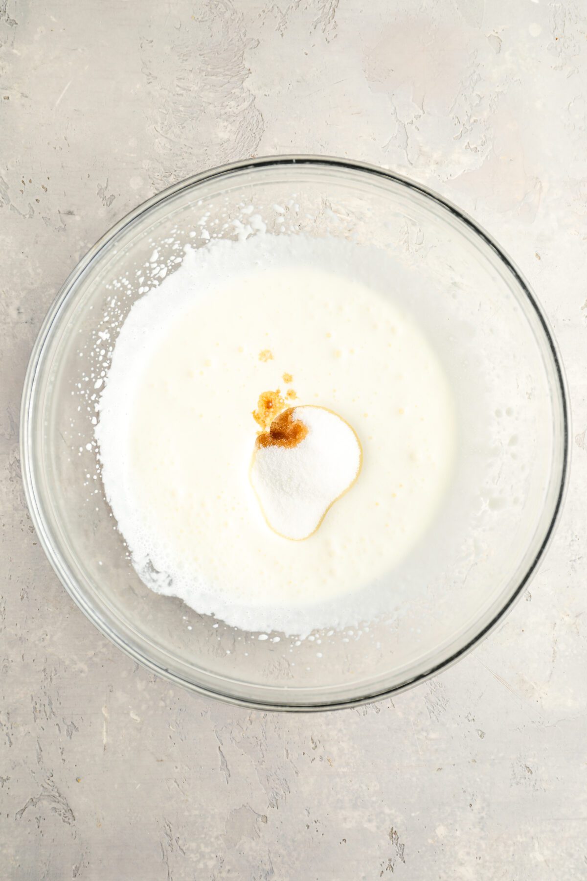 glass bowl with sugar and vanilla added to slightly thickened heavy cream