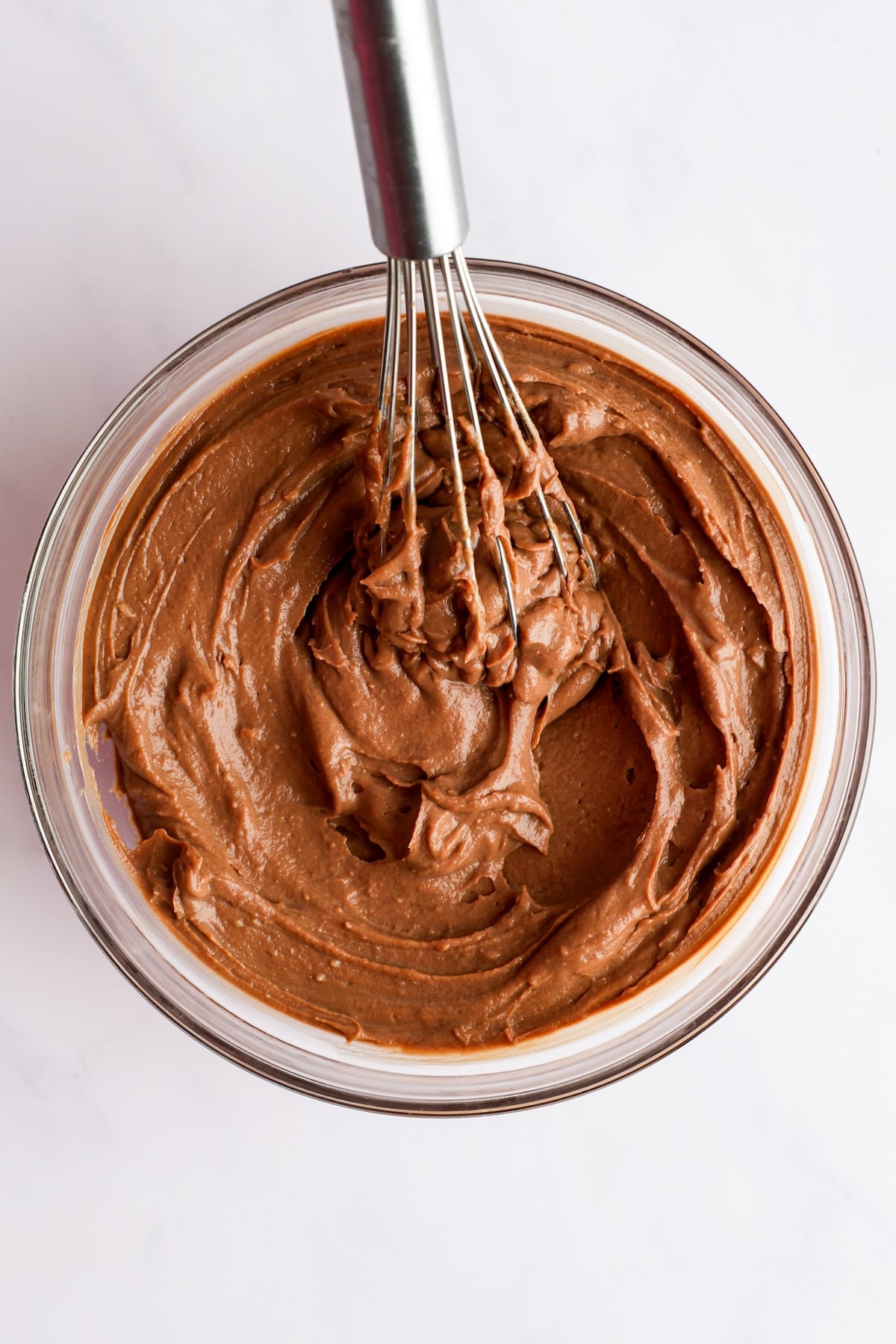 chilled chocolate pastry cream in glass bowl with whisk