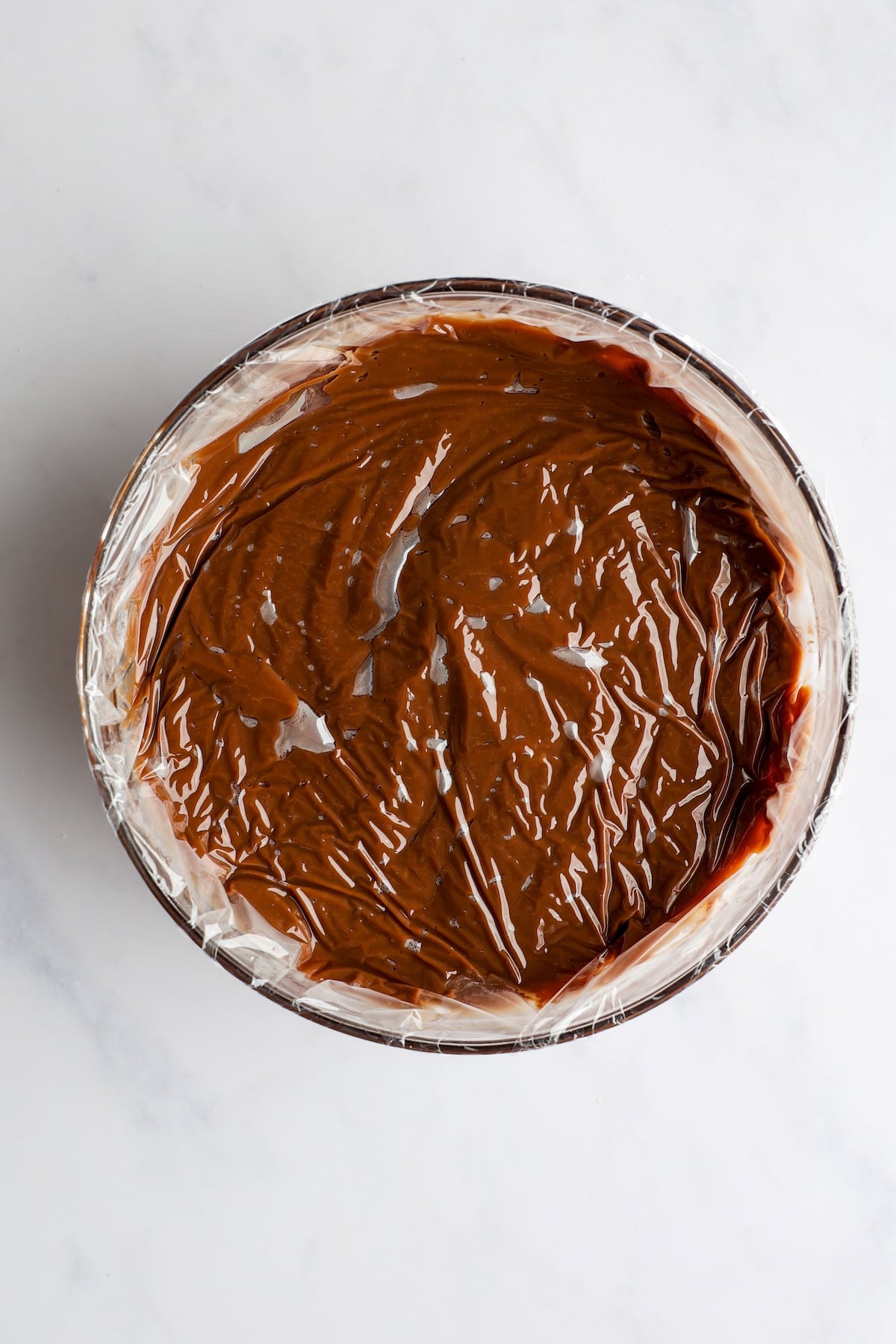 chocolate mixture covered with plastic wrap in glass bowl