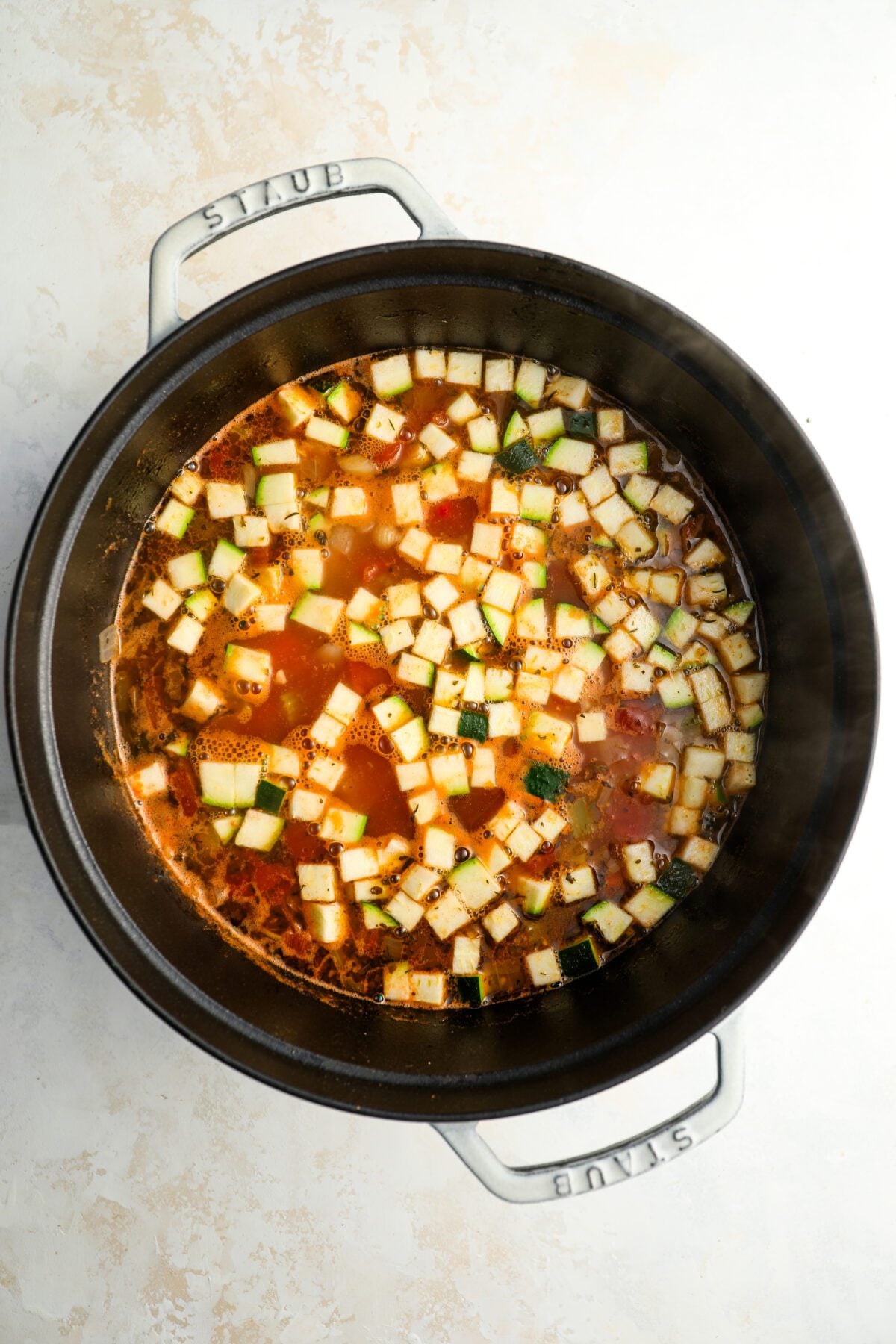 Dutch oven with zucchini and pasta added to soup mixture