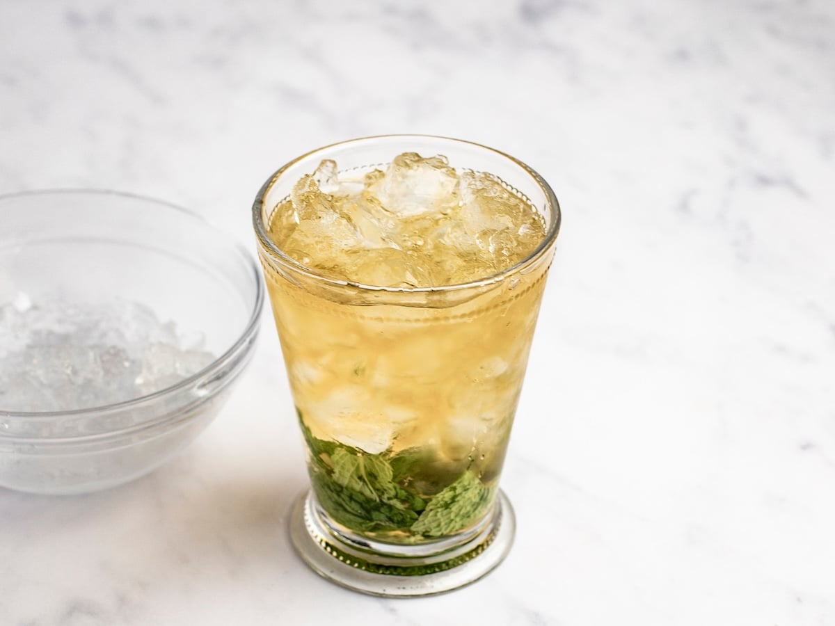 tall glass filled with ice, mint muddled in simple syrup and bourbon