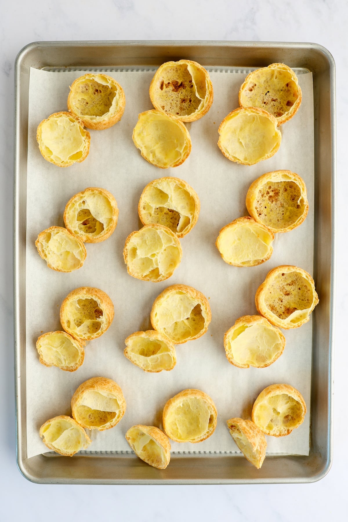 parchment line baking sheet with pastry shells cut in half