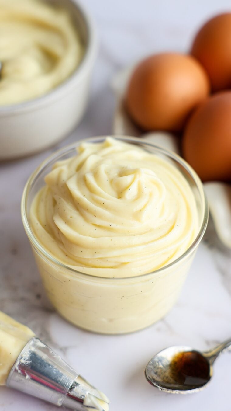 Vanilla pastry cream in bowl with eggs in the background.