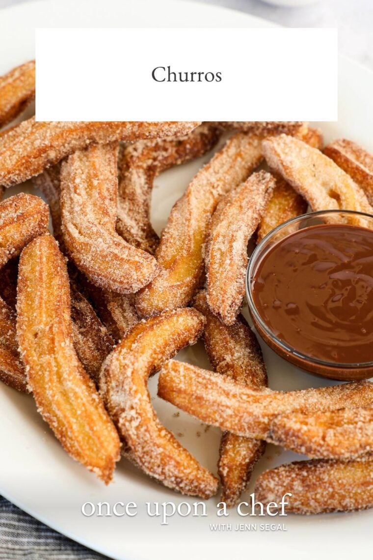 churros on white oval plate with bowl of chocolate sauce