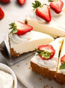 sliced no-bake cheesecake topped with strawberries on platter