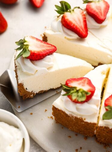 sliced no-bake cheesecake topped with strawberries on platter