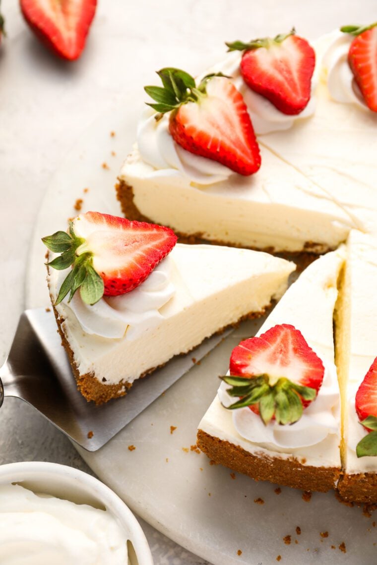 splatula lifitng one slice of strawberry topped no bake cheesecake