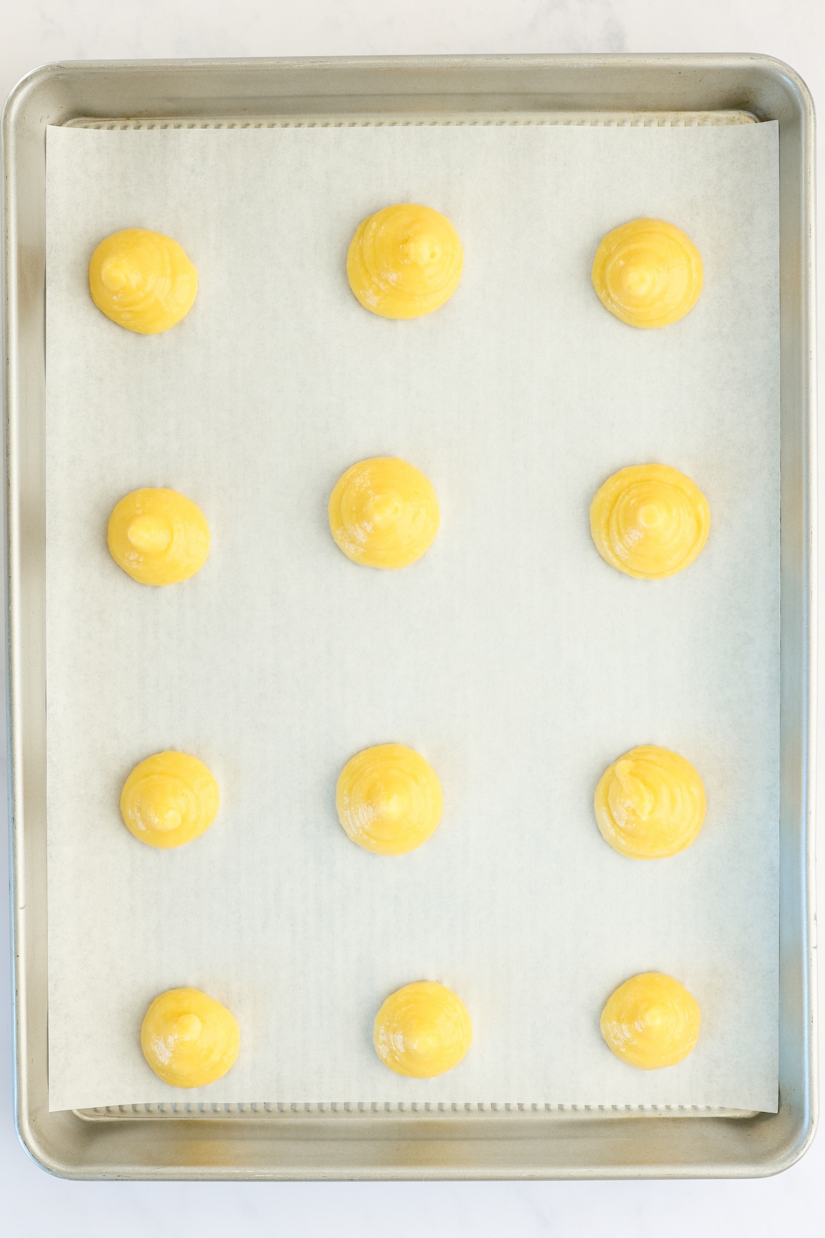 cream puff pastry piped onto baking sheet