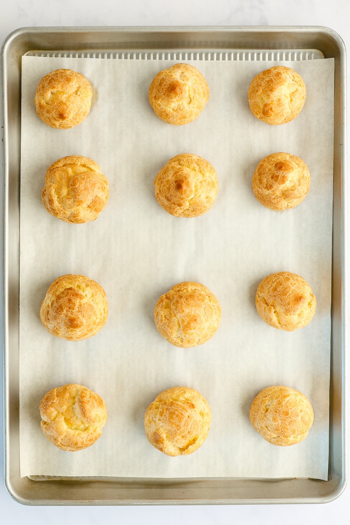 baked cream puffs on baking sheet
