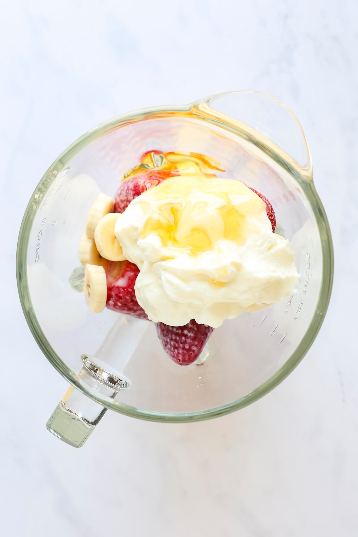 strawberries, banana, yogurt, milk, and honey in blender