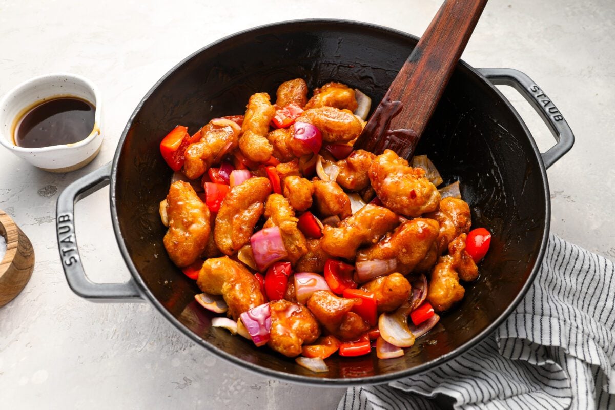 wok with cooked chicken and vegetables tossed with the sweet and sour sauce 
