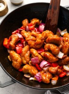 sweet and sour chicken in wok with wooden spoon and striped linen napkin