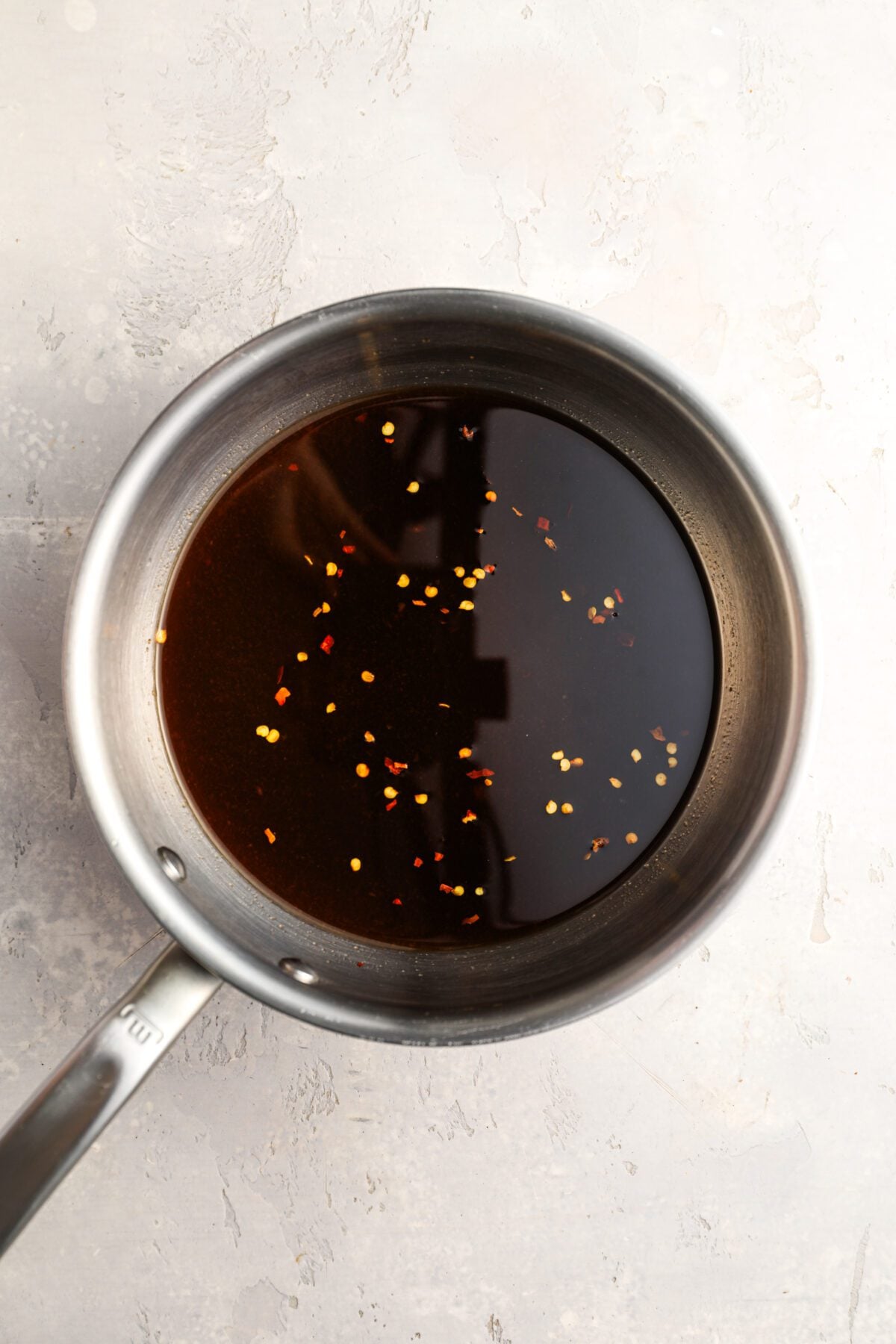 medium saucepan with pineapple juice, vinegar, sugar, ketchup, soy sauce, and red pepper flakes