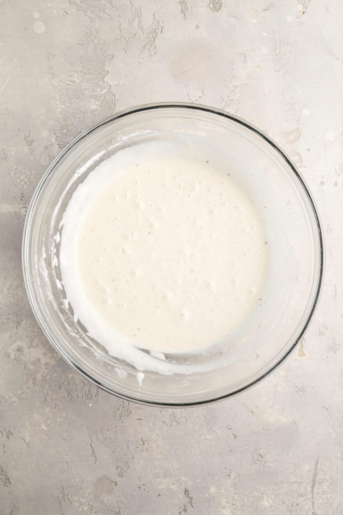 large bowl with flour, cornstarch, baking powder, baking soda, salt, pepper, water and oil mixed together to batter the chicken