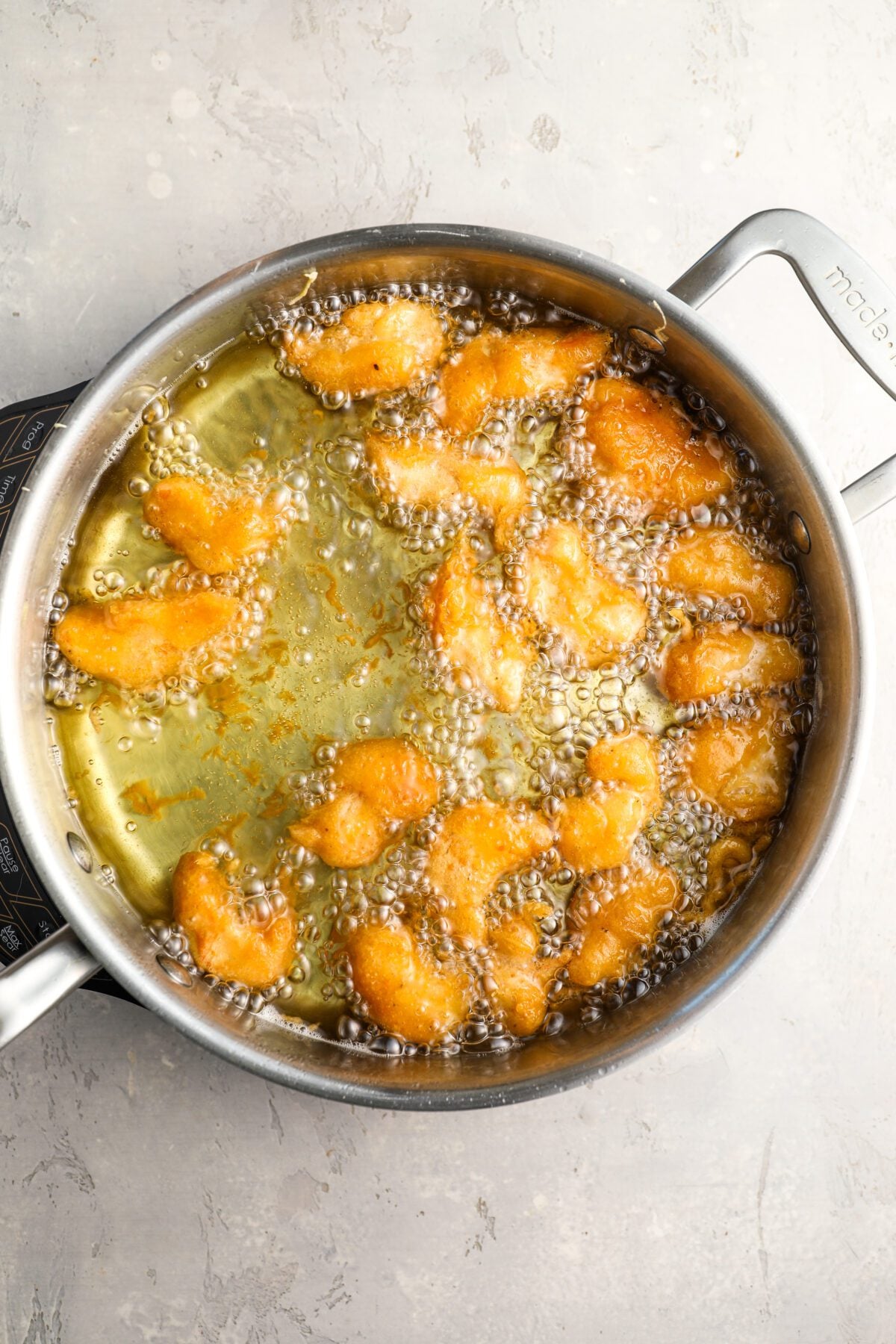 large, deep skillet with golden-brown breaded chicken pieces bubbling in oil