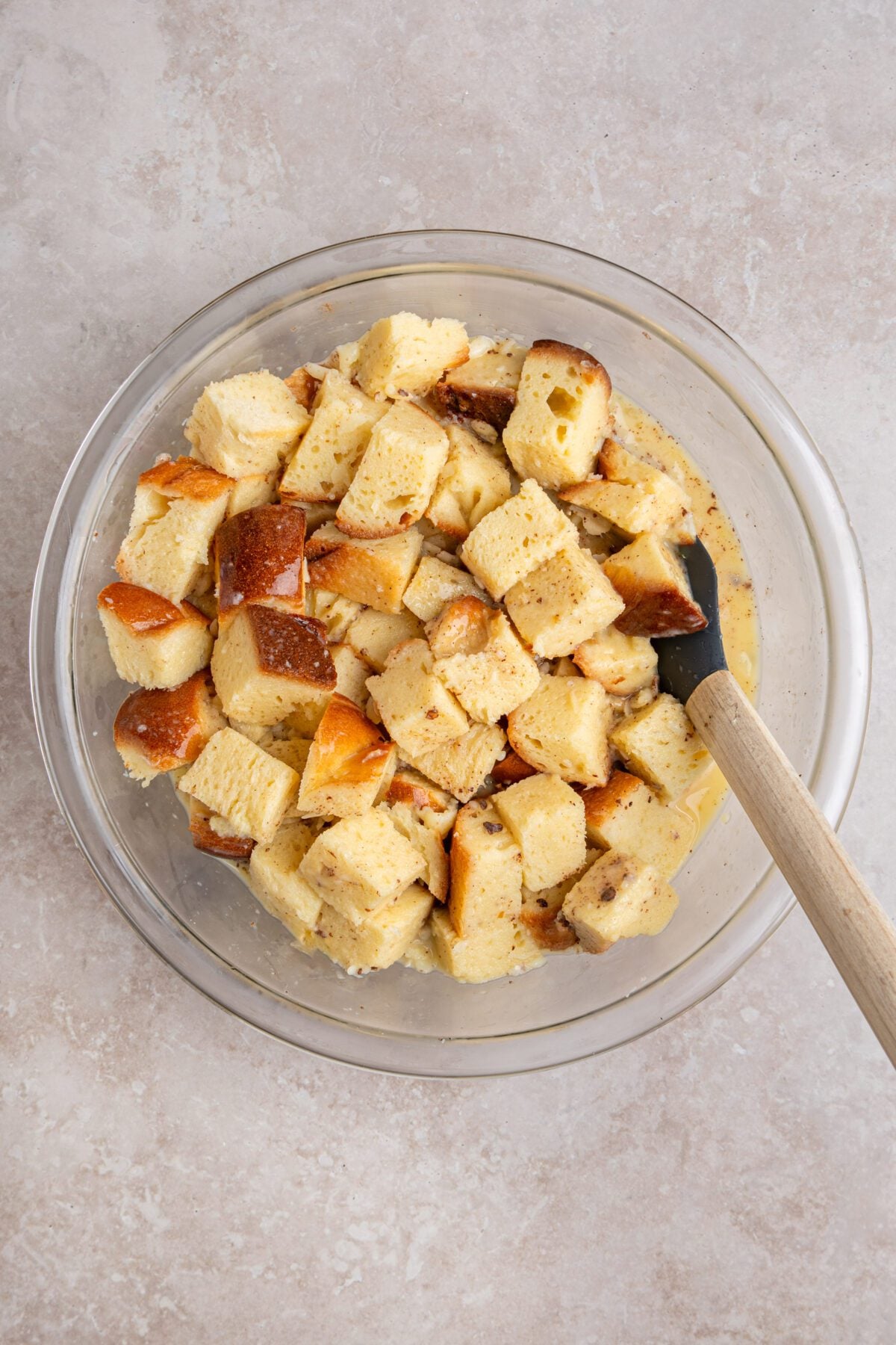 tossing bread cubes with the custard in mixing bowl