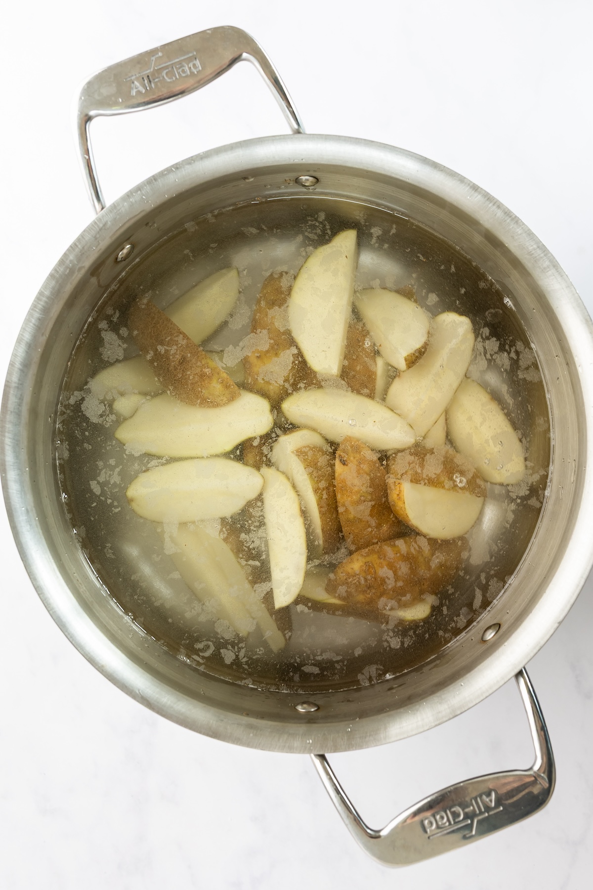 large pot with potato wedges in boiling water