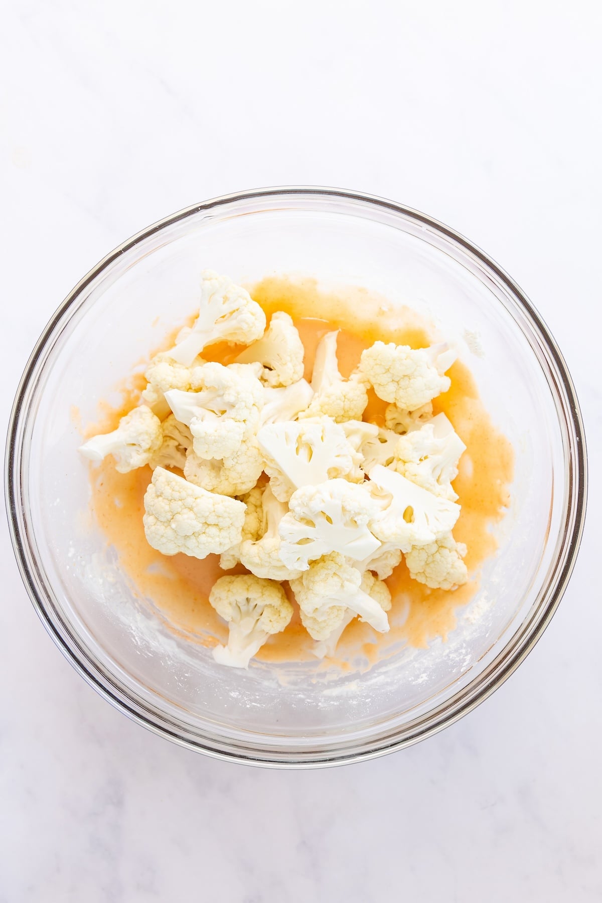 large bowl with cauliflower florets added to batter