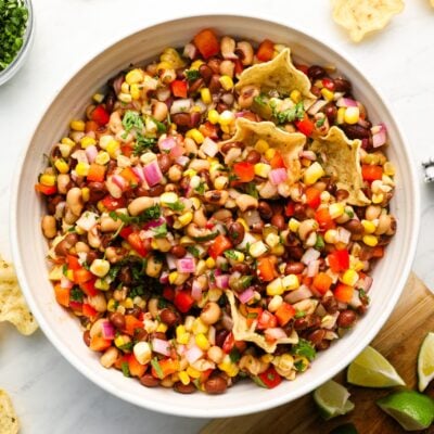 cowboy caviar in serving bowl with chips, cilantro and lime