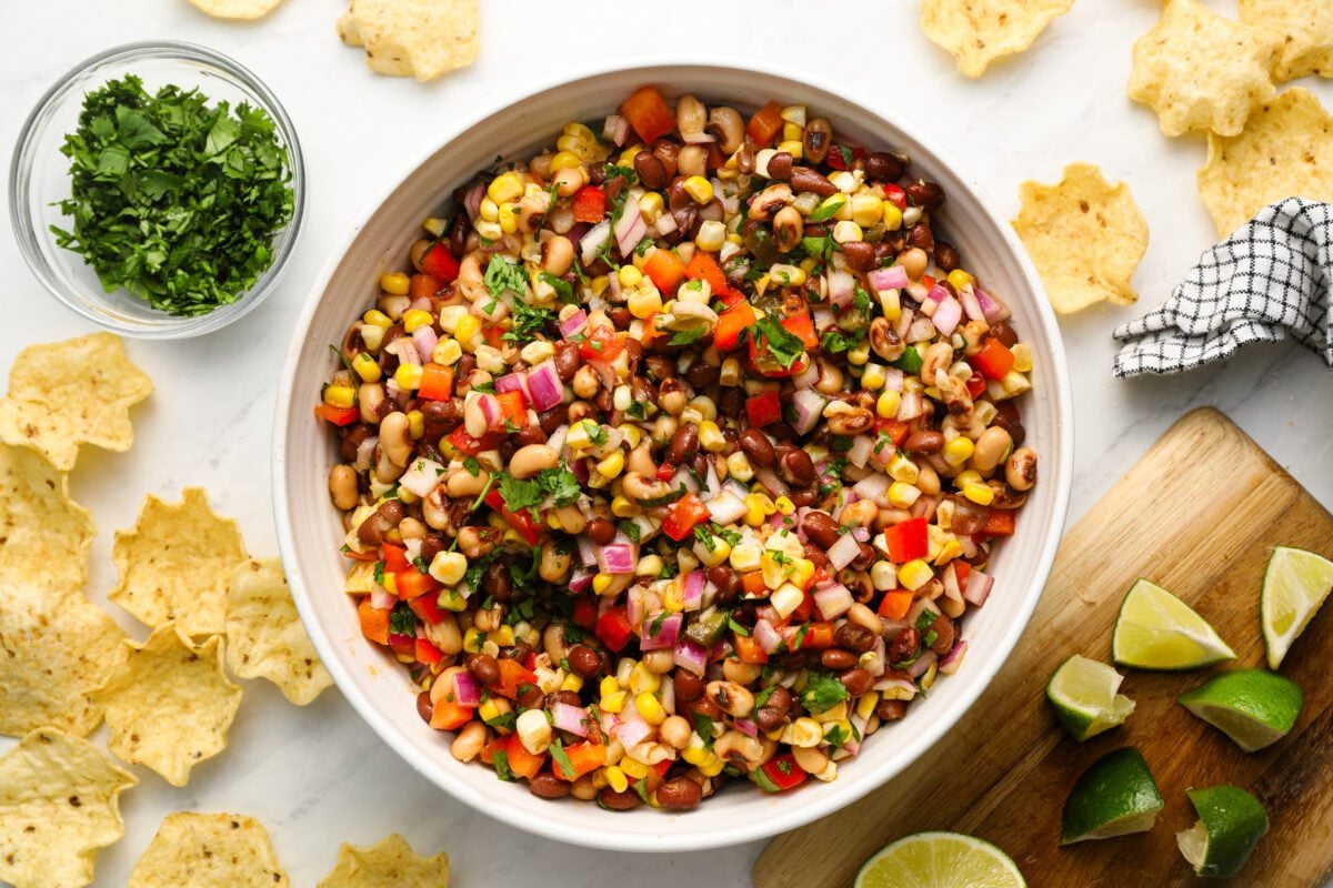 cowboy caviar in serving bowl with chips, cilantro and lime