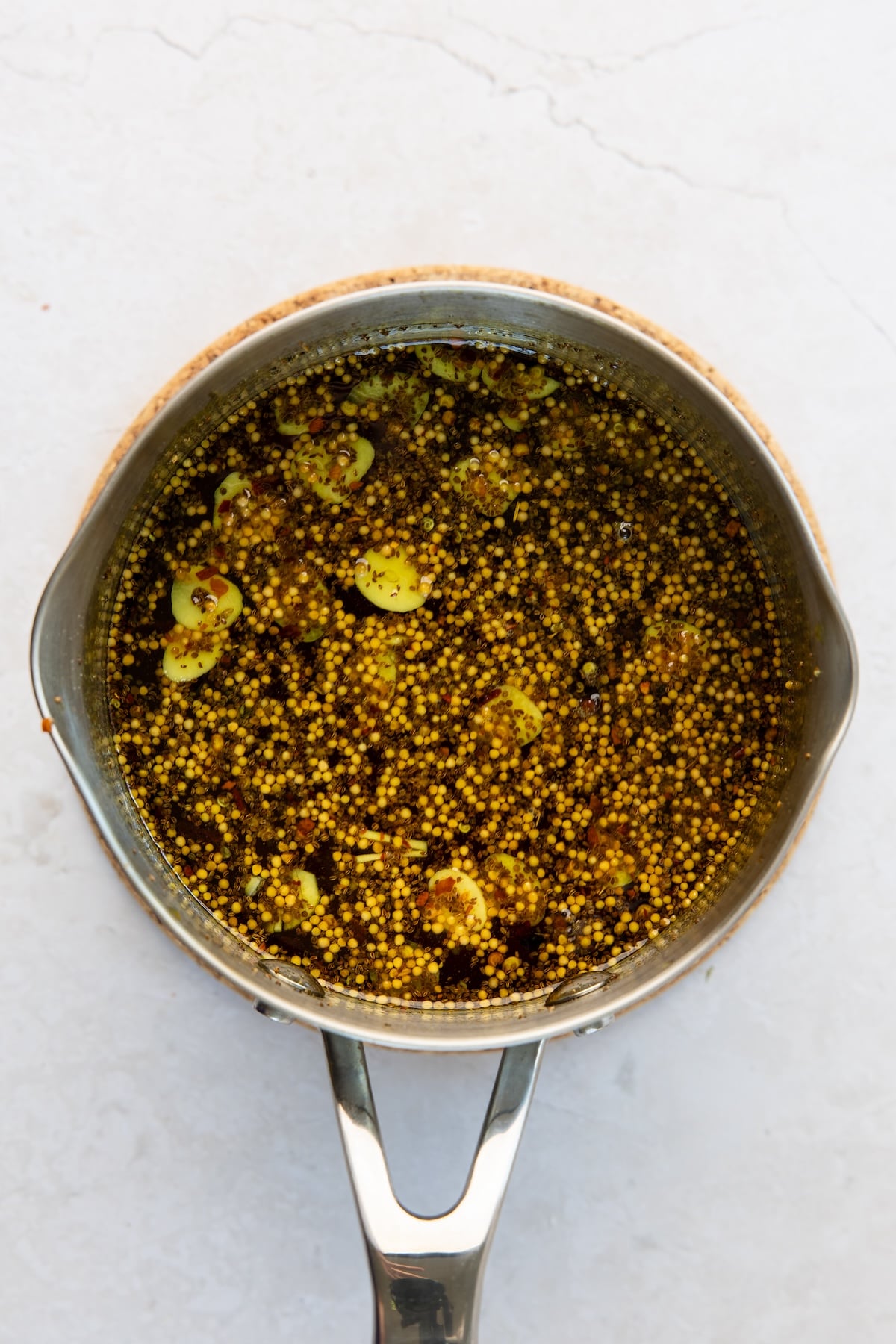 medium saucepan with simmered vinegar, granulated sugar, brown sugar, garlic, mustard seeds, celery seeds, turmeric, cloves, and red pepper flakes