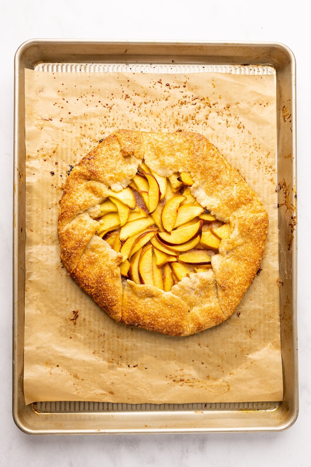 baked peach galette on parchment-lined baking sheet 