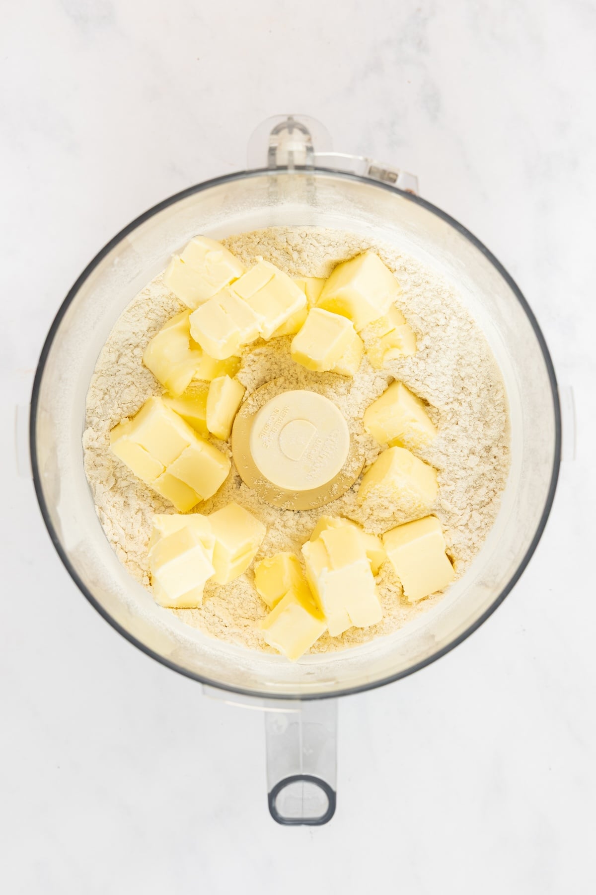food processor with flour, salt, and sugar and butter chunks