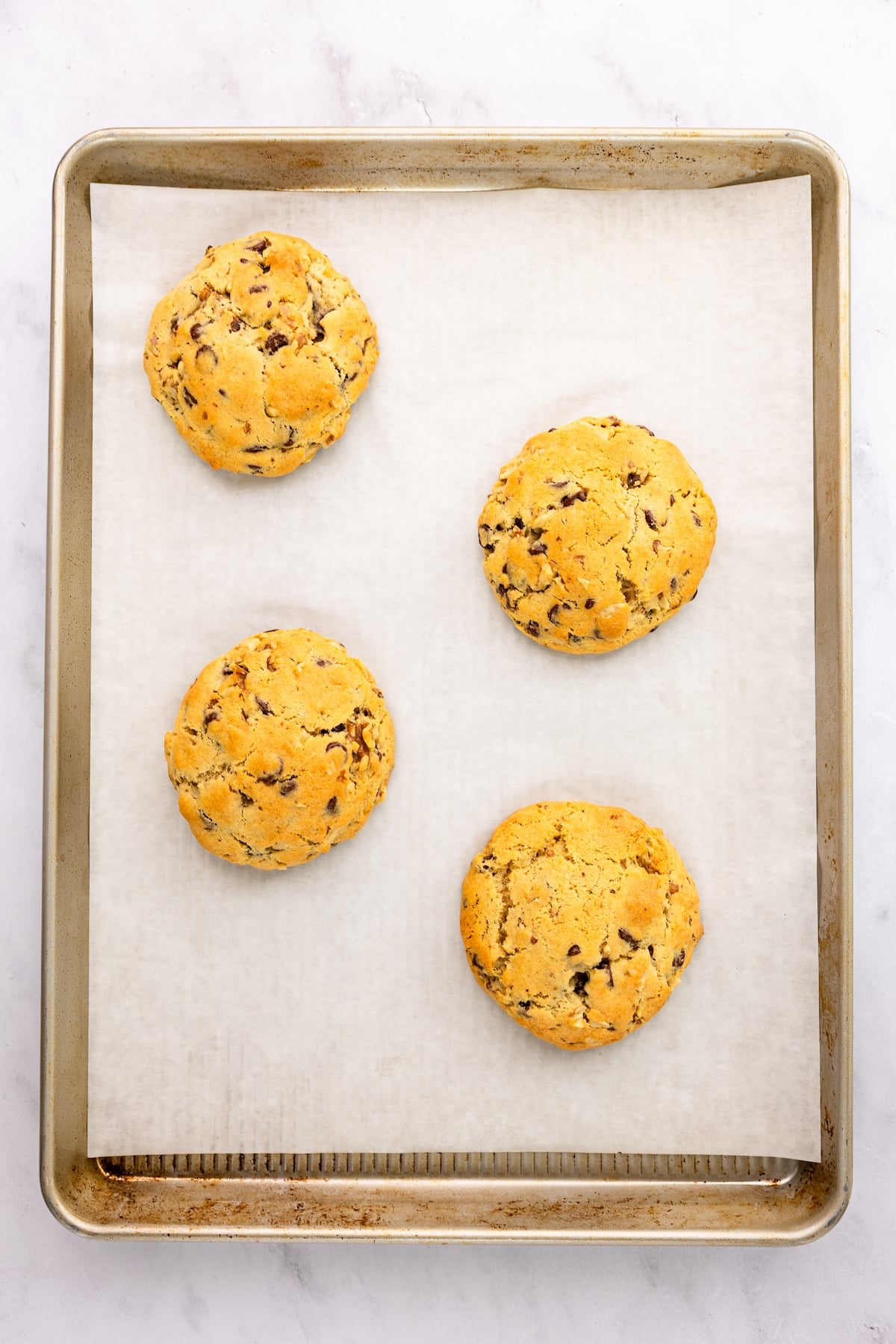parchment-lined baking sheet with 4 baked cookies