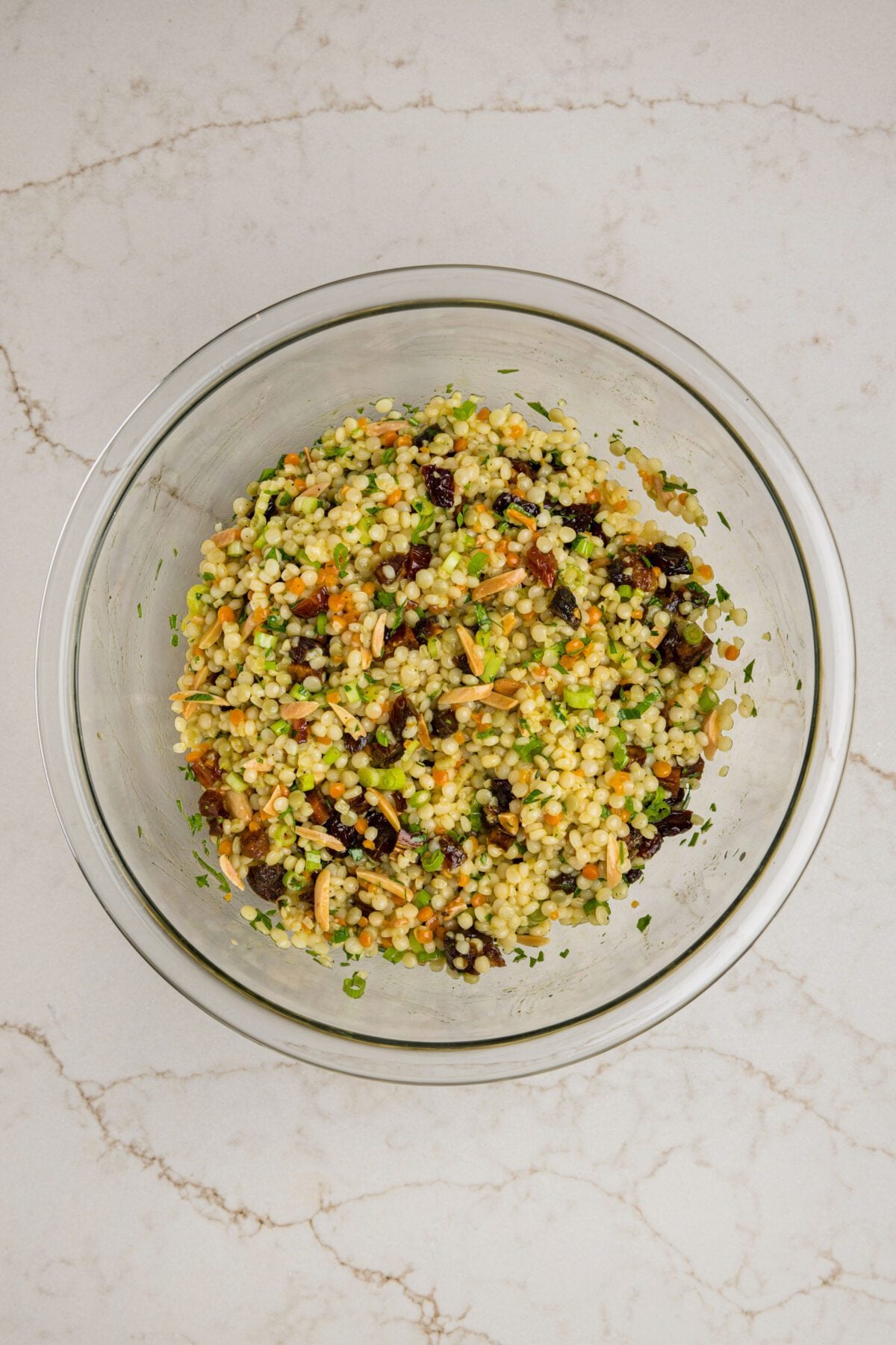 tossed israeli couscous salad in mixing bowl