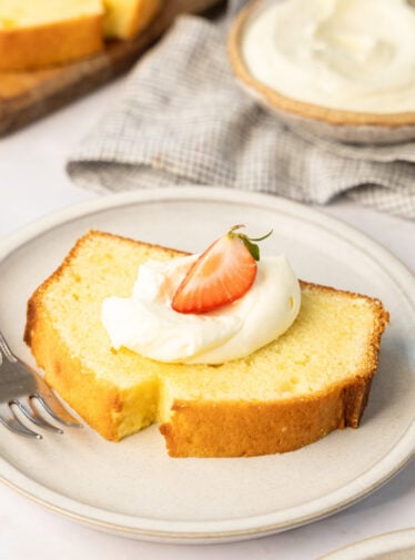 slice of cream cheese pound cake topped with whipped cream and strawberries