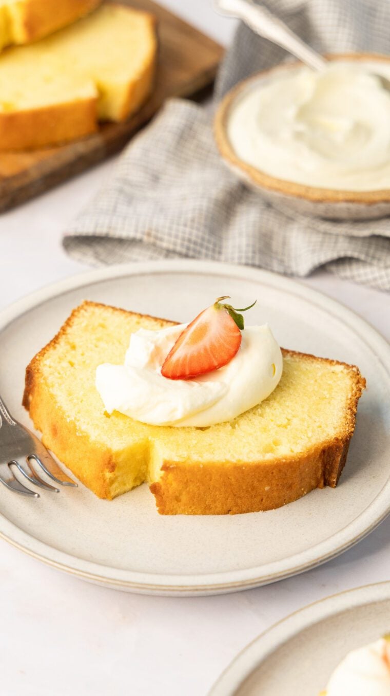slice of cream cheese pound cake topped with whipped cream and strawberries
