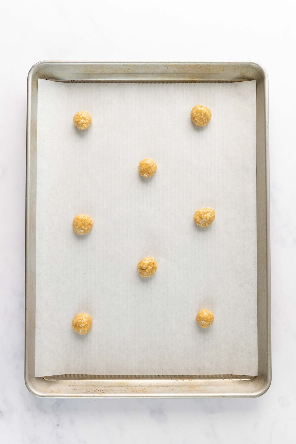 parchment-lined baking sheet with small dough balls
