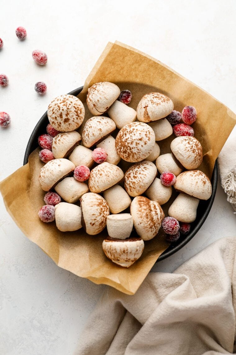 parchment lined bowl with meringue mushrooms scattered with sugared cranberries