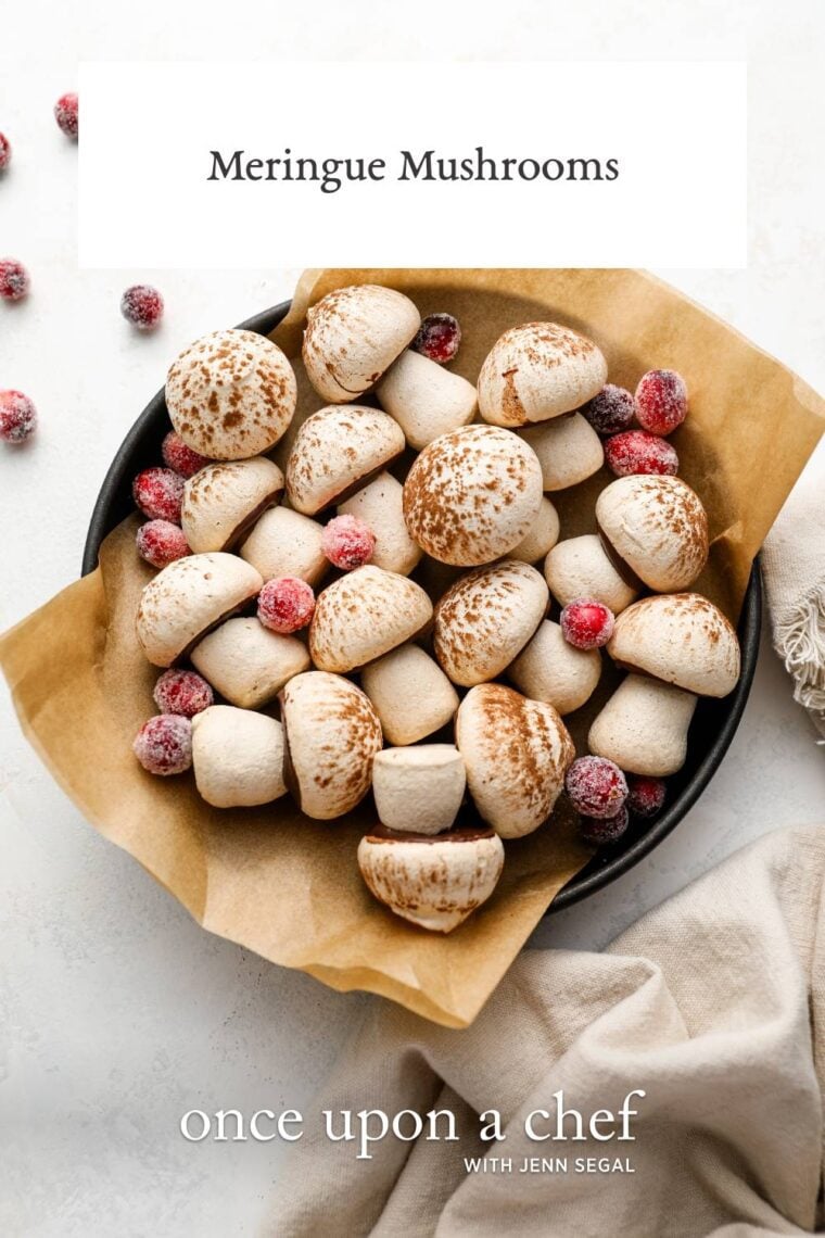 parchment-lined bowl filled with meringue mushrooms and dotted with sugared cranberries