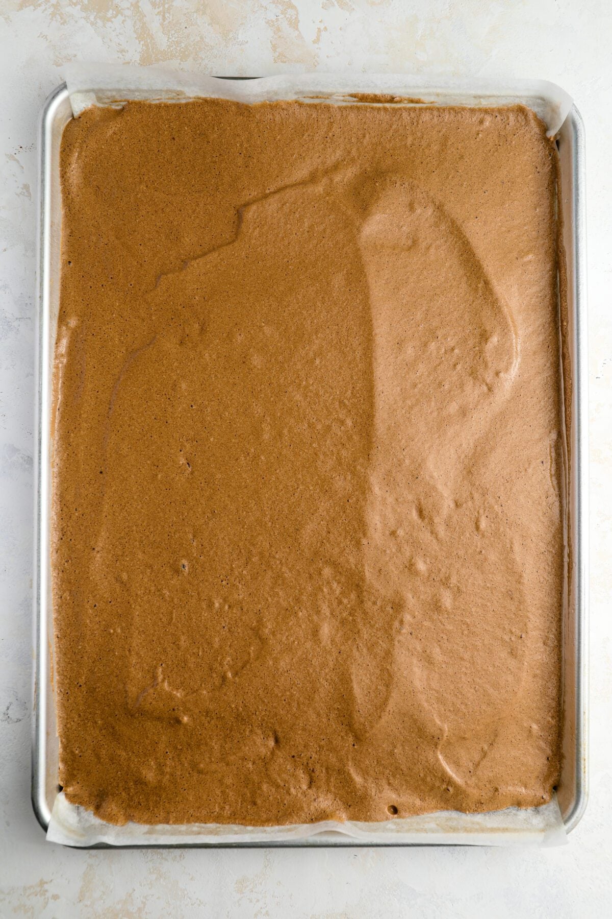 cake batter in parchment-lined jelly roll pan