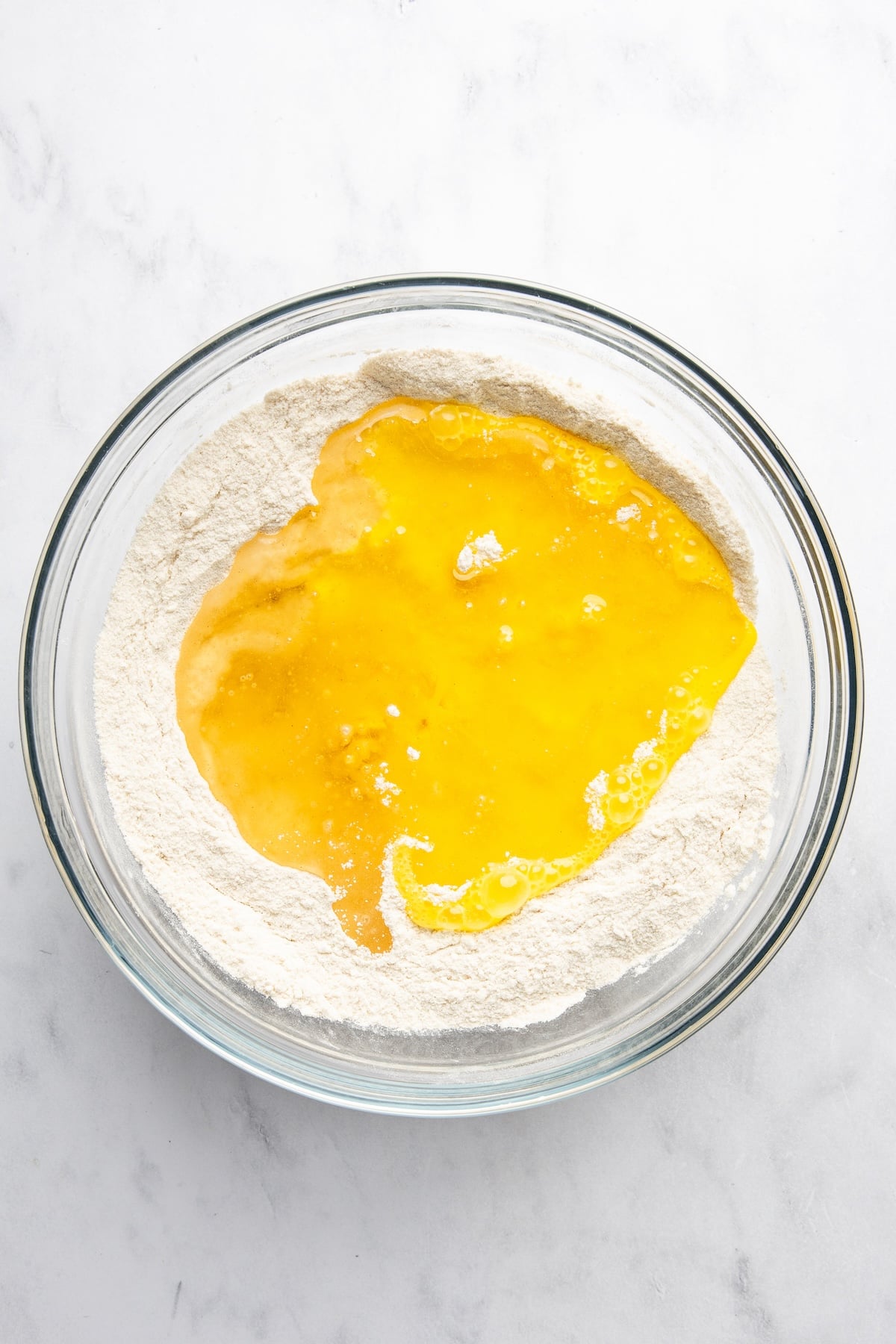 large bowl with eggs added to the flour, sugar, salt, baking soda, and cinnamon