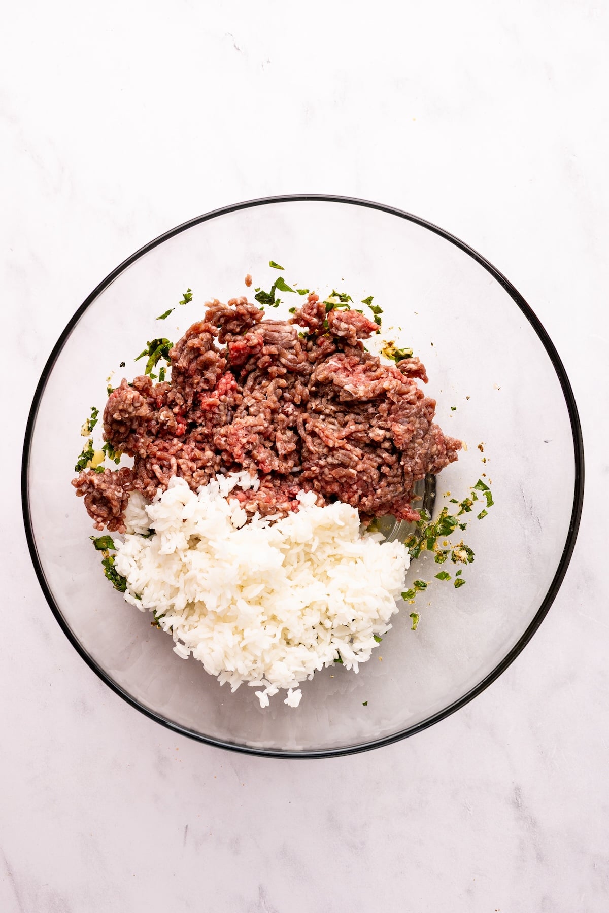 large bowl with meatloaf mix and cooked rice piled on top of egg and herb mixture