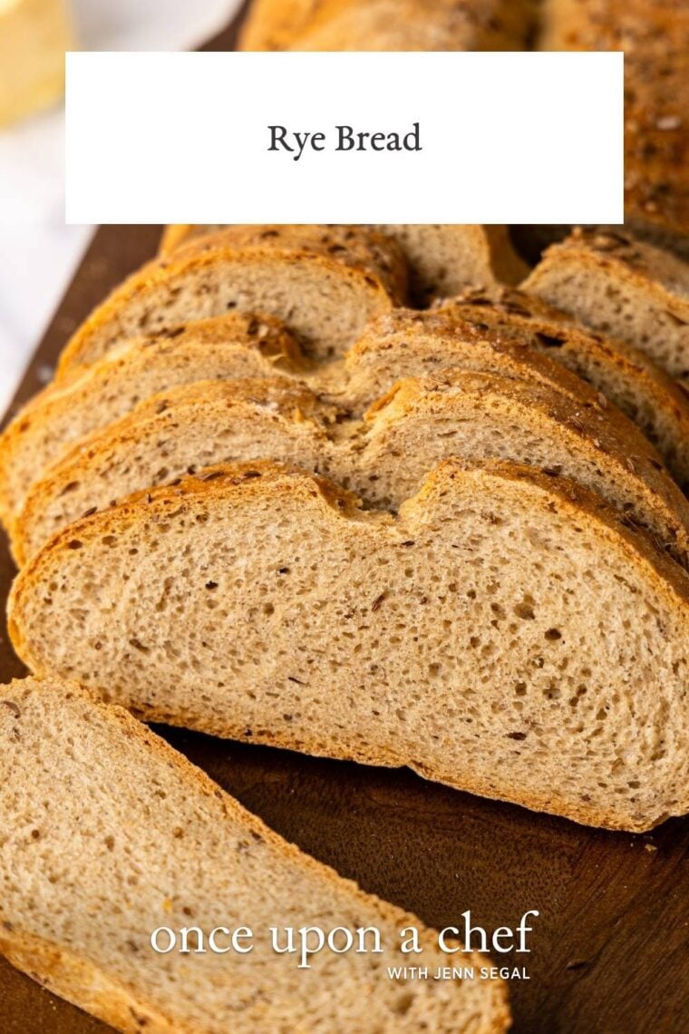 partially sliced loaf of rye bread on wood cutting board