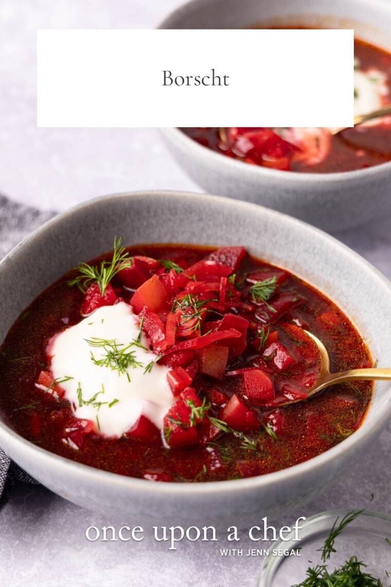 two bowls of borscht topped with sour cream and fresh dill