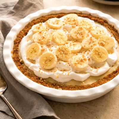 Banana cream pie with a linen napkin and stack of plates.