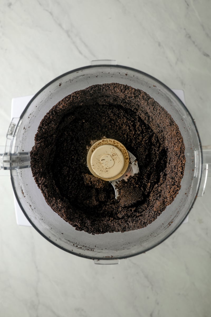 Crushed Oreo cookies in food processor bowl.